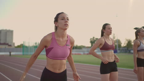 3-women-runners-prepare-for-the-long-distance-race-at-the-stadium-at-sunset-in-slow-motion